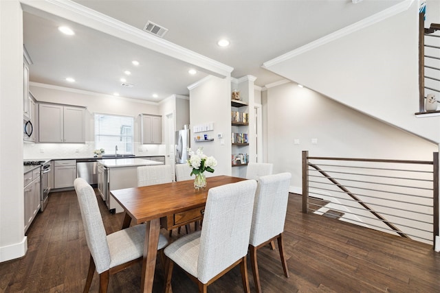 dining space with dark hardwood / wood-style flooring, ornamental molding, and sink