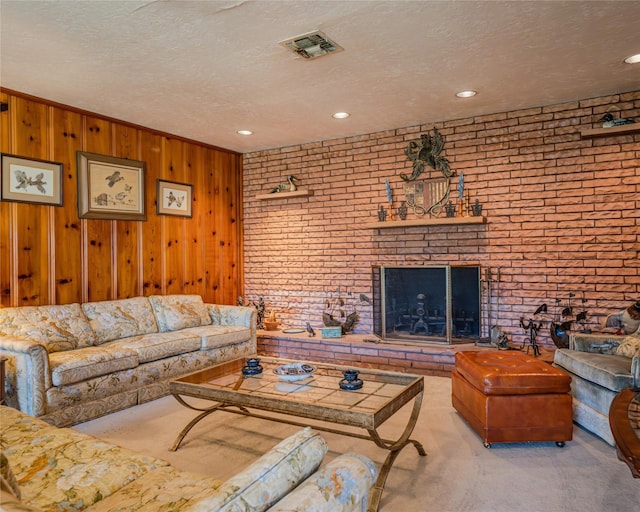 living room with a fireplace, light colored carpet, a textured ceiling, and wooden walls