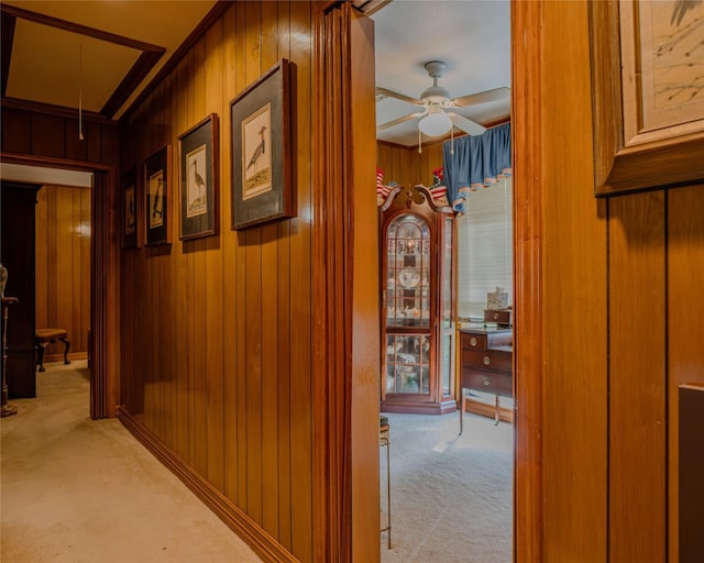 hallway featuring light carpet and wooden walls