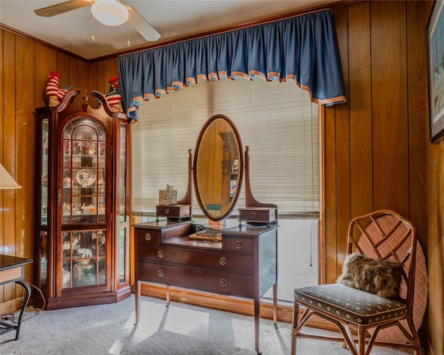 sitting room with light carpet, ceiling fan, crown molding, and wood walls