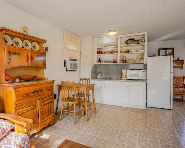 kitchen featuring white cabinets, white appliances, and a textured ceiling