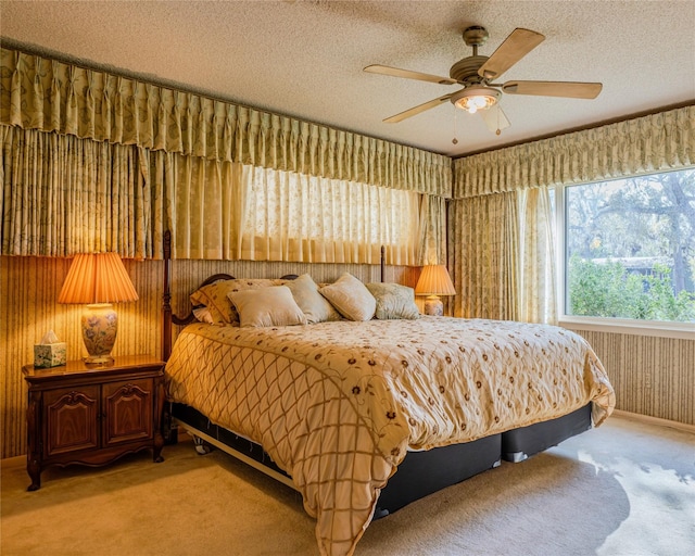 bedroom with a textured ceiling, carpet floors, ceiling fan, and wood walls