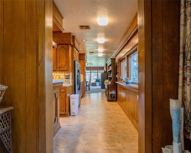 corridor with wood walls and a textured ceiling