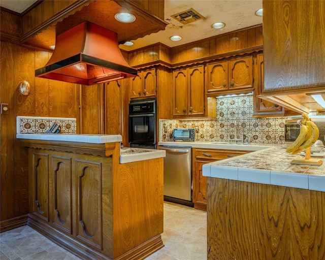 kitchen featuring custom exhaust hood, sink, stainless steel dishwasher, tasteful backsplash, and kitchen peninsula