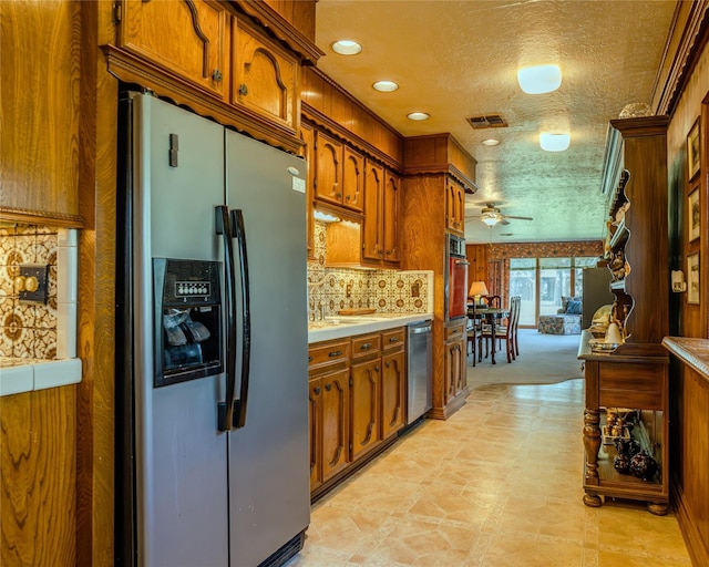 kitchen with appliances with stainless steel finishes, tasteful backsplash, a textured ceiling, ceiling fan, and sink