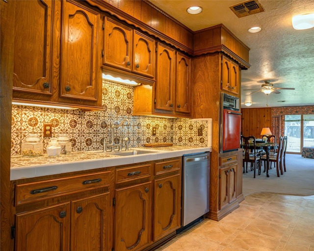 kitchen with tile countertops, backsplash, sink, ceiling fan, and stainless steel appliances