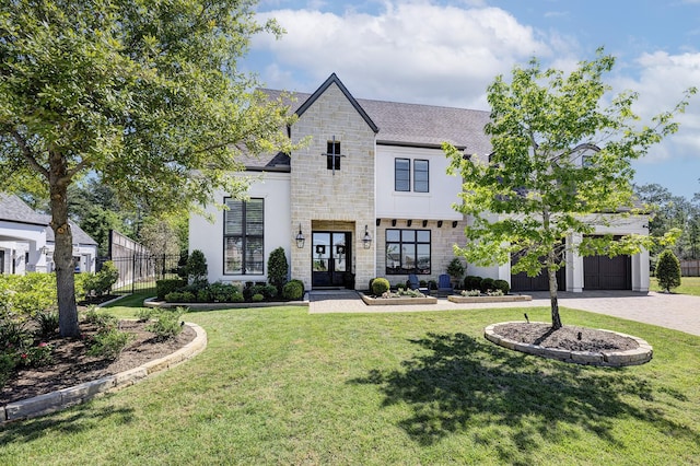 french country inspired facade with a garage, a front yard, and french doors