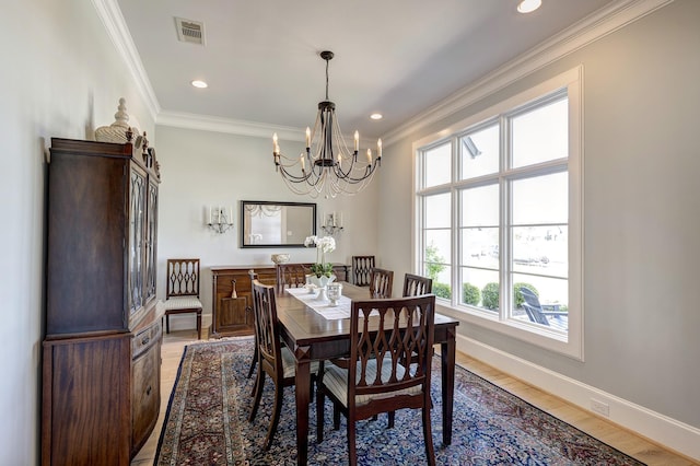 dining room featuring light hardwood / wood-style flooring, crown molding, and an inviting chandelier