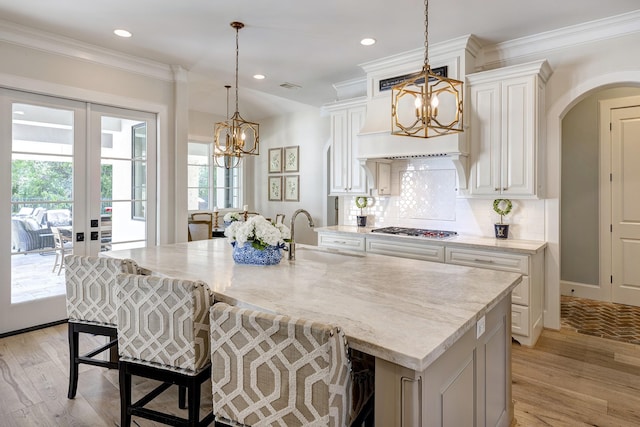 kitchen with decorative backsplash, a large island with sink, french doors, and sink