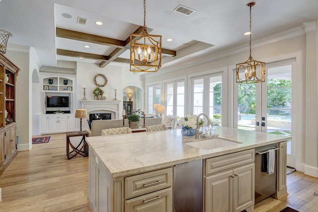 kitchen with beamed ceiling, decorative light fixtures, a center island with sink, and sink