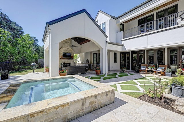 view of pool with an outdoor living space with a fireplace, ceiling fan, and a patio