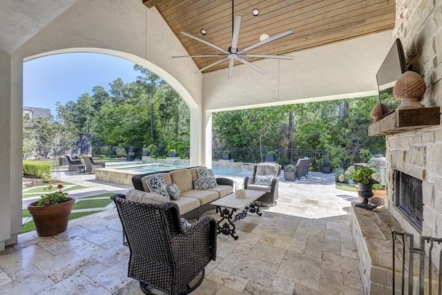 view of patio featuring an outdoor stone fireplace, ceiling fan, and a fenced in pool