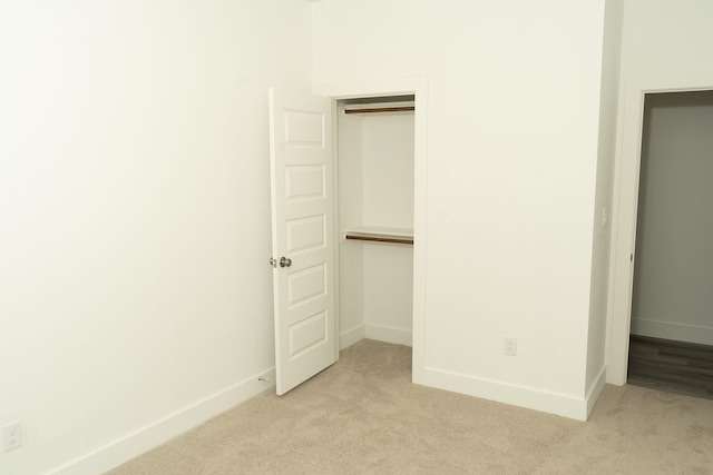 unfurnished bedroom featuring light colored carpet and a closet