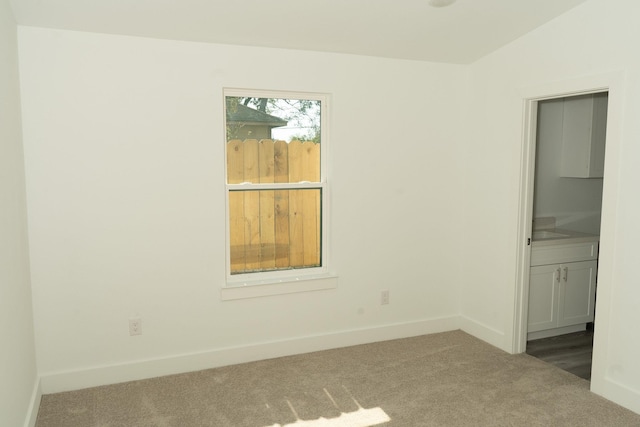 carpeted spare room featuring vaulted ceiling