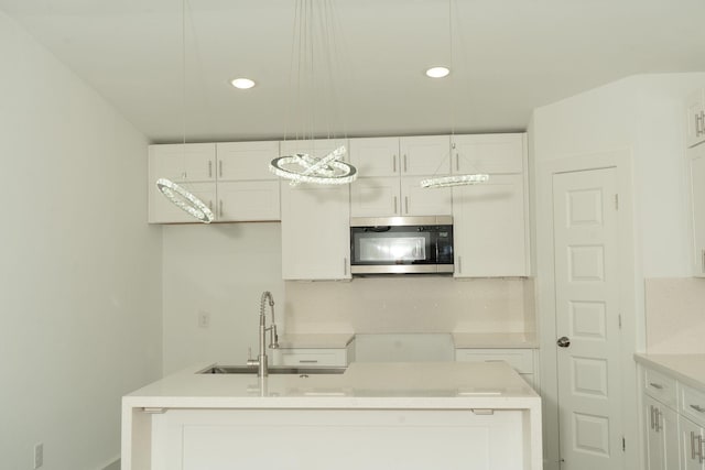 kitchen with decorative light fixtures, white cabinetry, and sink