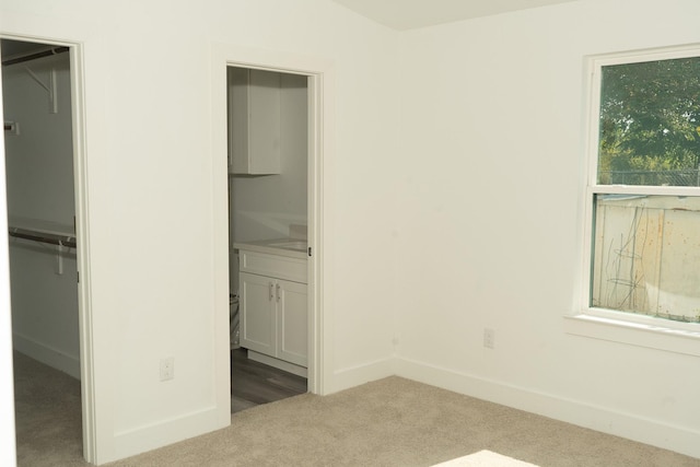 unfurnished bedroom featuring carpet, a walk in closet, and a closet