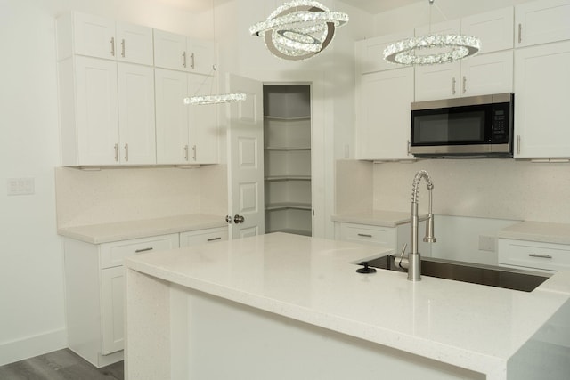 kitchen featuring white cabinets, decorative light fixtures, sink, and a notable chandelier