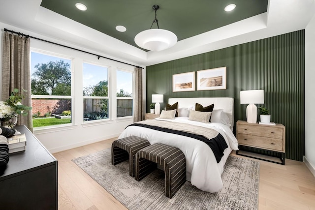 bedroom featuring light wood-type flooring and a tray ceiling