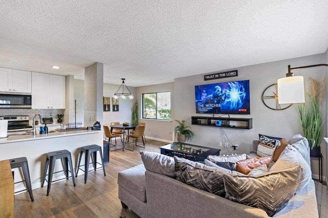 living room with a textured ceiling, hardwood / wood-style flooring, and an inviting chandelier