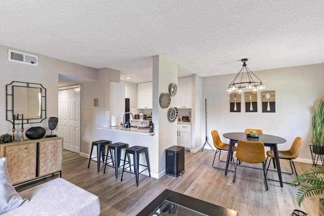 dining space with hardwood / wood-style floors, a textured ceiling, and a chandelier