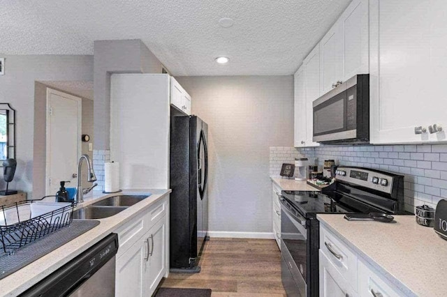 kitchen featuring appliances with stainless steel finishes, a textured ceiling, sink, white cabinets, and hardwood / wood-style floors