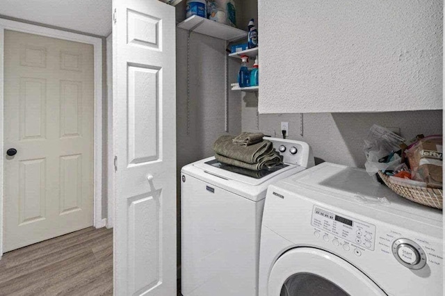 clothes washing area featuring washer and dryer and light hardwood / wood-style flooring