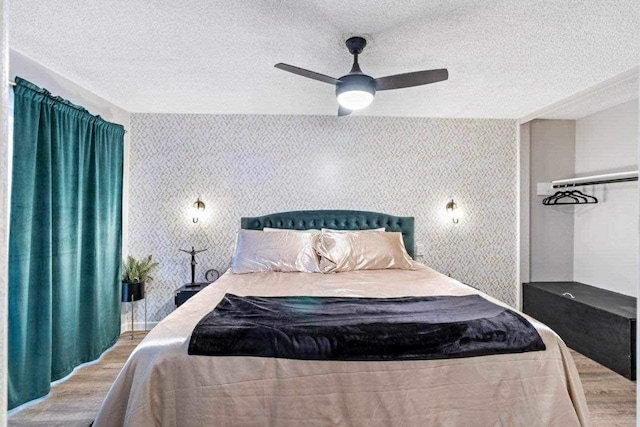 bedroom with a textured ceiling, light hardwood / wood-style flooring, and ceiling fan