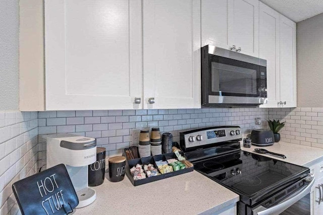 kitchen with backsplash, black / electric stove, white cabinetry, and light stone countertops