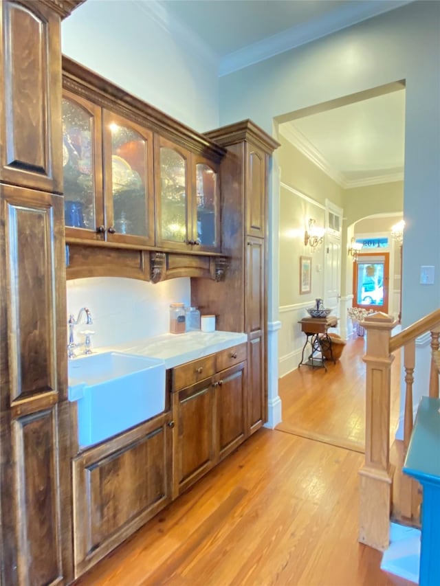 kitchen with light hardwood / wood-style flooring, ornamental molding, and sink