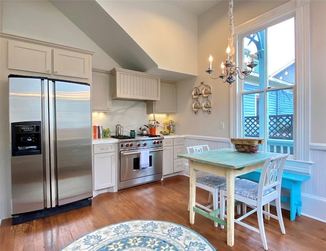 kitchen featuring dark hardwood / wood-style flooring, backsplash, stainless steel appliances, pendant lighting, and a notable chandelier