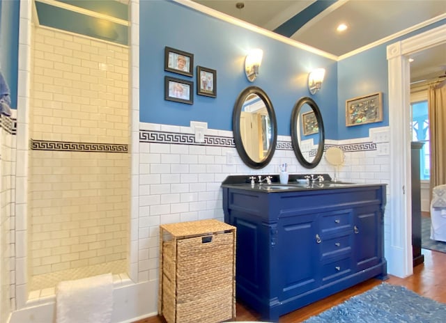 bathroom featuring vanity, ornamental molding, tiled shower, tile walls, and wood-type flooring