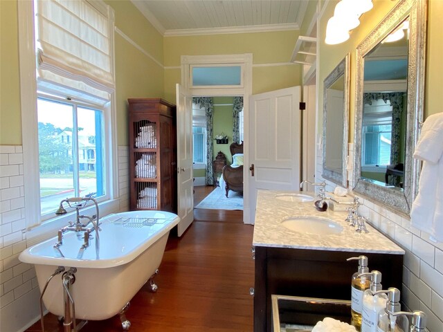 bathroom featuring hardwood / wood-style flooring, a washtub, vanity, and ornamental molding