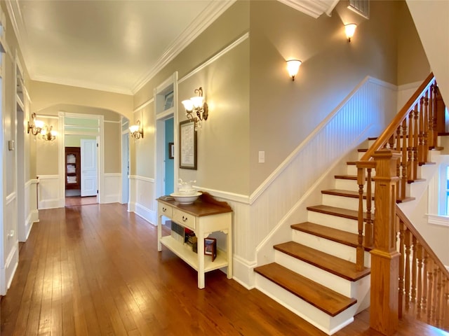 stairs featuring built in features, wood-type flooring, and ornamental molding