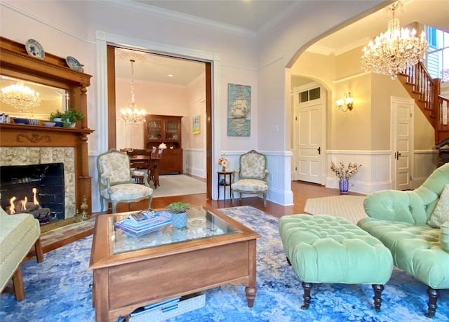 sitting room featuring a chandelier, hardwood / wood-style flooring, a stone fireplace, and crown molding