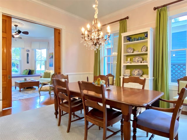 dining area with wood-type flooring, ceiling fan with notable chandelier, and crown molding