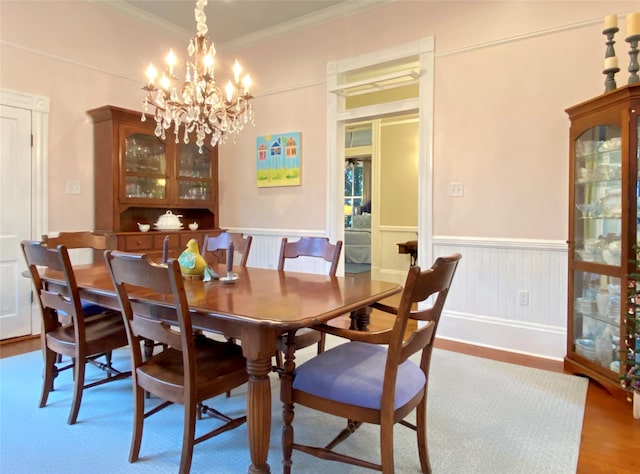 dining area with hardwood / wood-style flooring, ornamental molding, and a chandelier