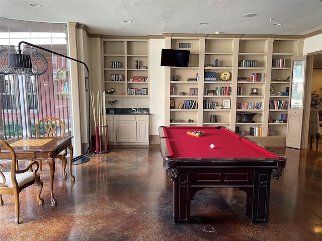 game room with built in shelves, a healthy amount of sunlight, a textured ceiling, and billiards