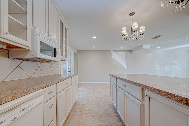 kitchen featuring tasteful backsplash, white appliances, pendant lighting, light tile patterned floors, and an inviting chandelier