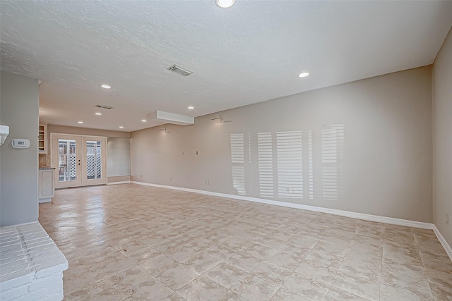 unfurnished room featuring french doors and a textured ceiling