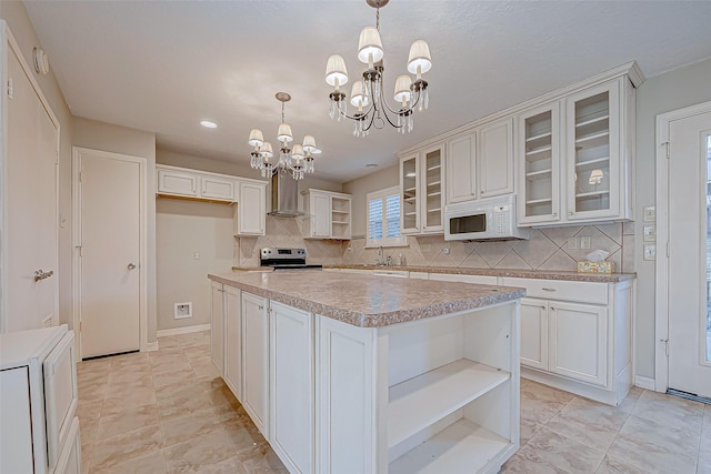 kitchen featuring white cabinetry, electric range, a center island, wall chimney exhaust hood, and a chandelier