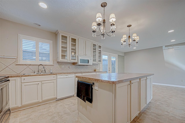 kitchen with a center island, hanging light fixtures, a notable chandelier, white appliances, and decorative backsplash