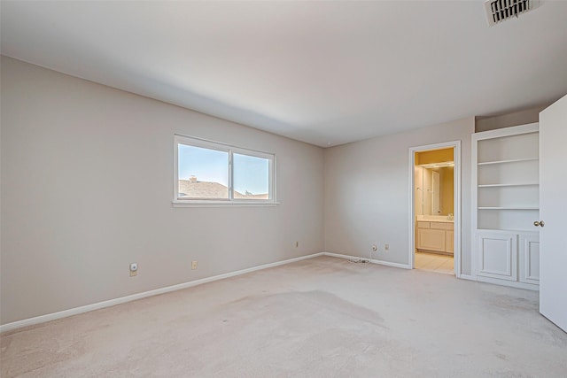 spare room with built in shelves and light colored carpet