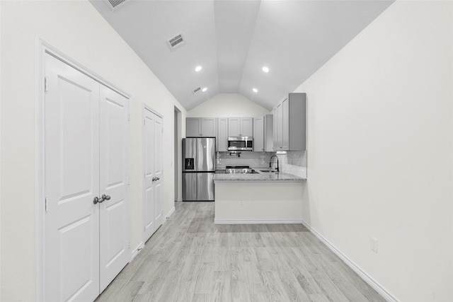 kitchen featuring light stone countertops, sink, stainless steel appliances, vaulted ceiling, and gray cabinets