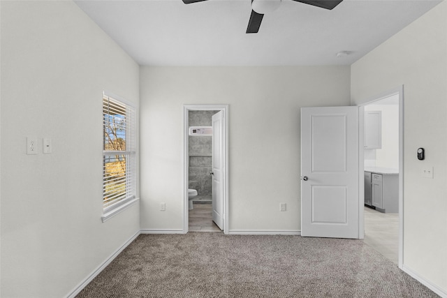 unfurnished bedroom featuring light carpet, ensuite bathroom, and ceiling fan