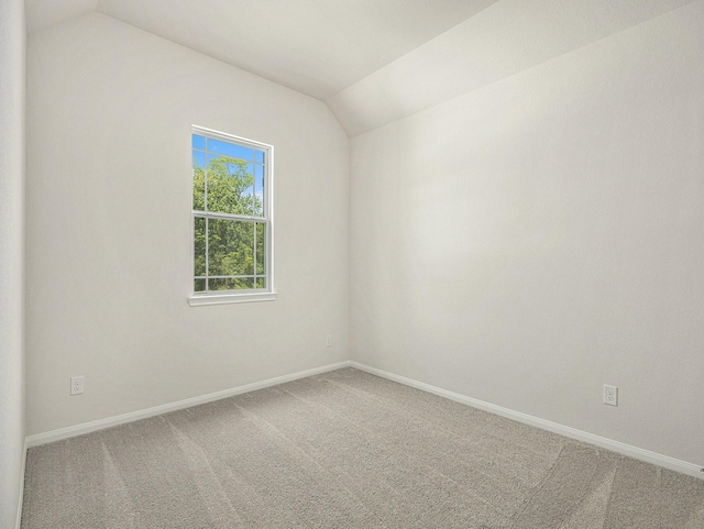 carpeted empty room featuring vaulted ceiling