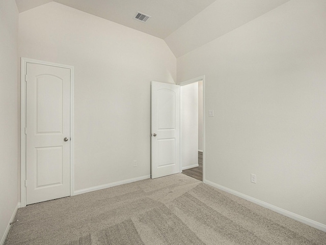 carpeted empty room with lofted ceiling