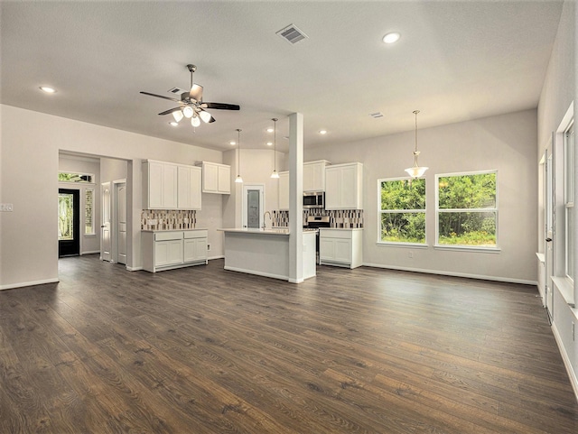 kitchen with a kitchen island with sink, tasteful backsplash, decorative light fixtures, white cabinetry, and stainless steel appliances