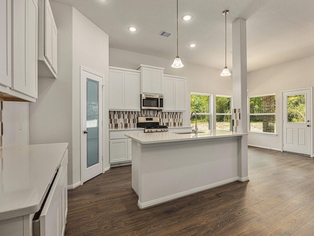 kitchen with sink, hanging light fixtures, stainless steel appliances, an island with sink, and white cabinets