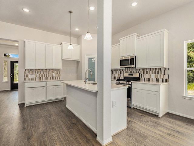 kitchen with tasteful backsplash, stainless steel appliances, sink, decorative light fixtures, and white cabinets