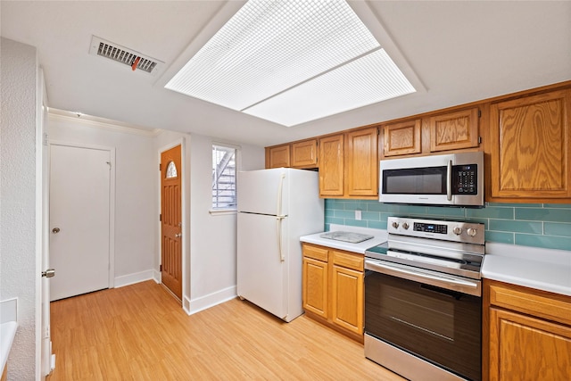 kitchen with backsplash, stainless steel appliances, and light hardwood / wood-style floors